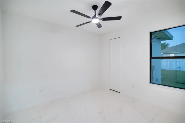 Unfurnished room featuring light marble finish floors and ceiling fan