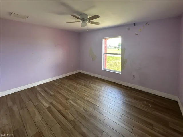 Interior space featuring wood-finish flooring, a ceiling fan with integrated lighting, and a window providing natural light