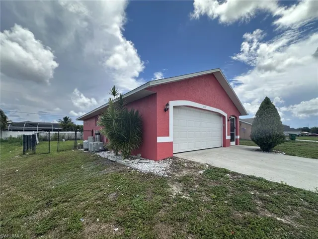 Pink stucco exterior featuring a white garage door with an arched frame and exterior sconces