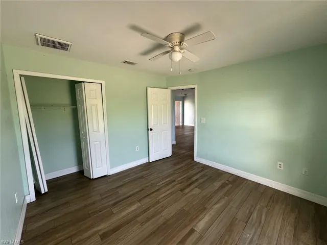 Room featuring wood-look tile flooring, light green painted walls, and white baseboards