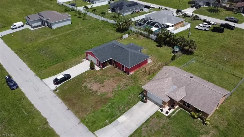 Single-story residence featuring a red exterior, dark shingle roof, and a front-facing garage with a concrete driveway