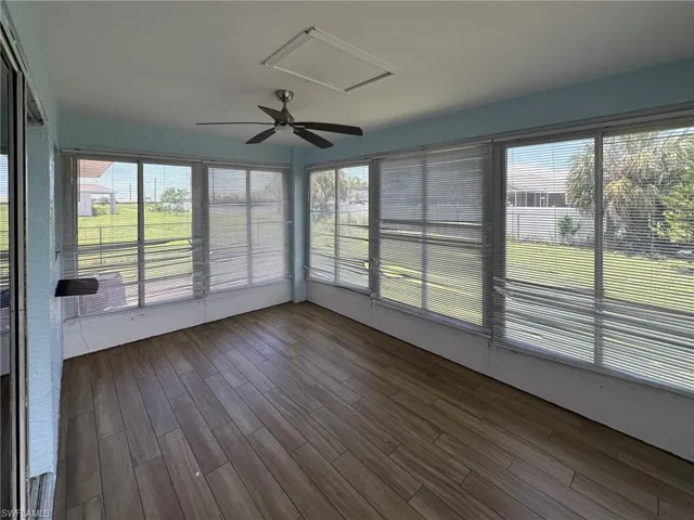 Enclosed sunroom featuring wood-finish flooring, a ceiling fan, and multiple large windows with blinds