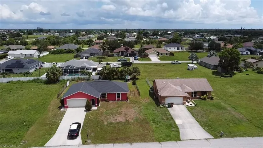 Aerial view showcasing two single-story residences with attached garages and paved driveways