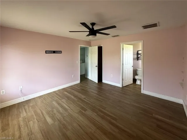 Spacious room featuring wood-finish flooring, a ceiling fan, and white baseboards