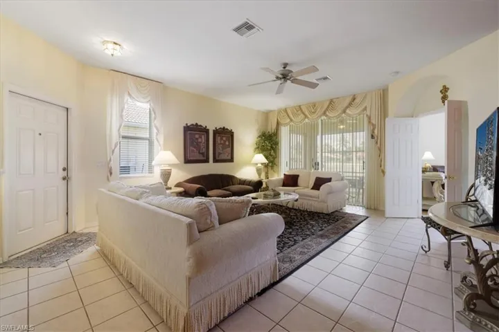 Living area featuring light tile patterned floors, ceiling fan, and arched walkways