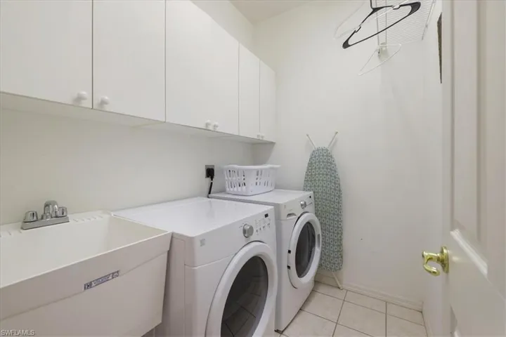 Laundry area featuring cabinet space, washer and clothes dryer, and light tile patterned floors
