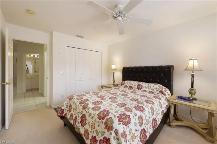 Bedroom with a closet, a ceiling fan, and light carpet