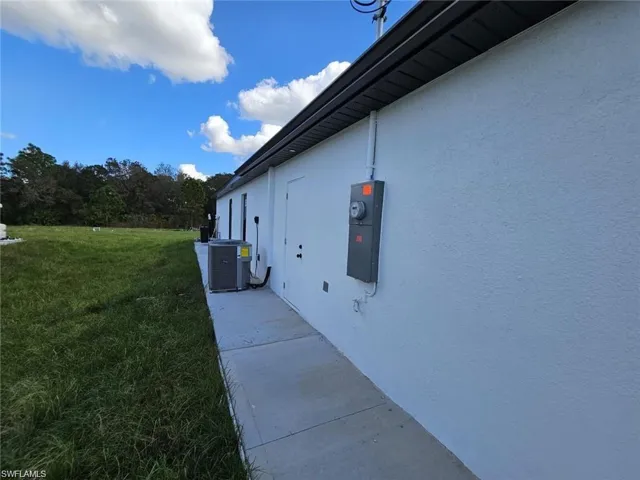 View of property exterior with a yard and central AC unit