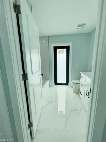 Bathroom featuring toilet, vanity, and a bathtub