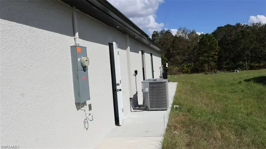 View of side of home with central AC and a yard