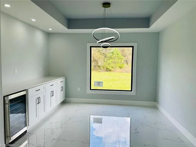 Unfurnished dining area featuring a tray ceiling and beverage cooler