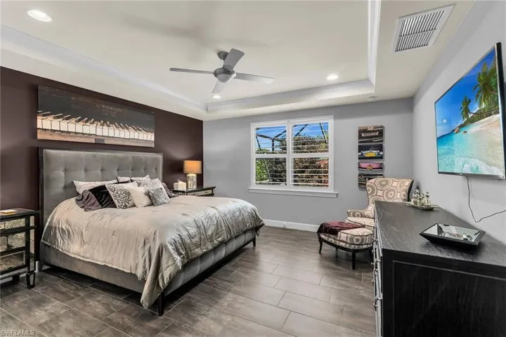 Bedroom featuring a ceiling fan, recessed lighting, and a tray ceiling