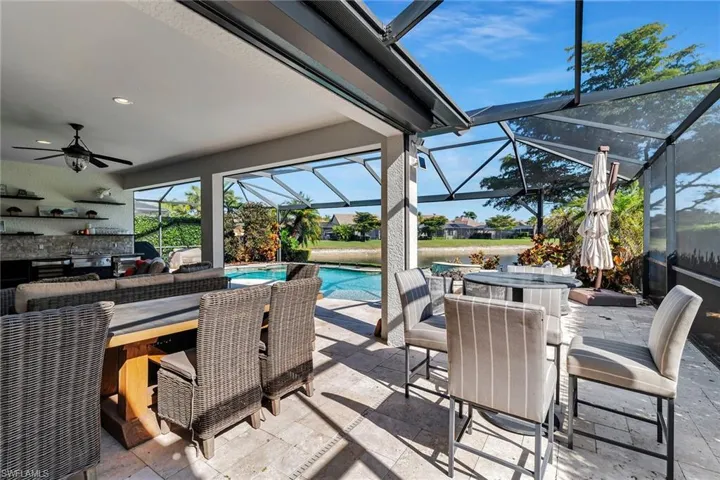 View of patio with outdoor dining space, ceiling fan, a sunroom, and glass enclosure