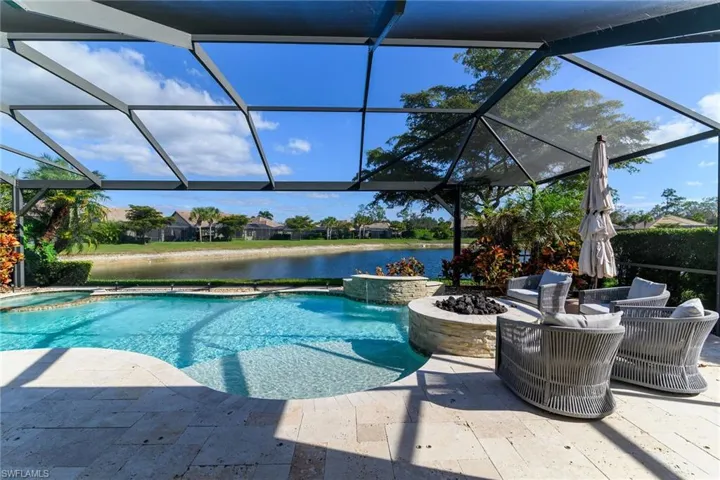 Outdoor pool with a hot tub, a water view, a lanai, and a sunroom