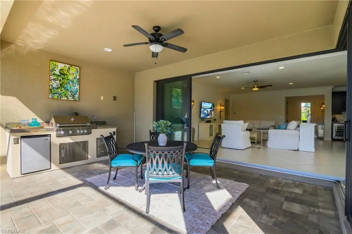 View of patio / terrace featuring area for grilling, a ceiling fan, outdoor dining space, and beverage cooler