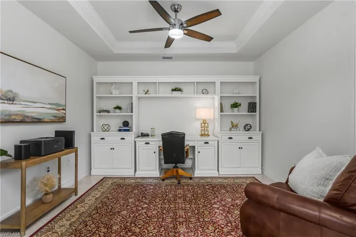 Office featuring crown molding, a ceiling fan, and a tray ceiling