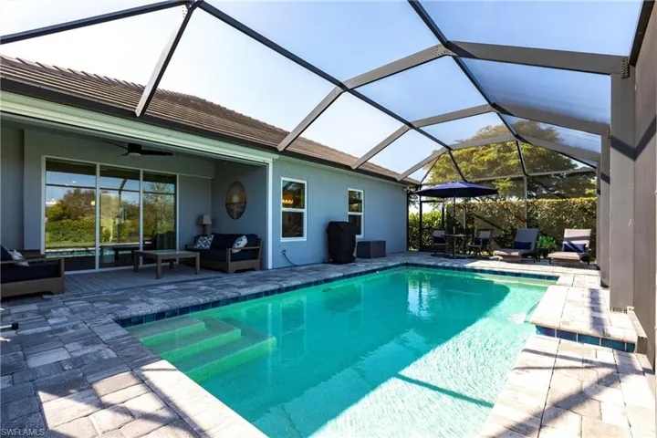 View of swimming pool with an outdoor living space, a patio area and ceiling fan.