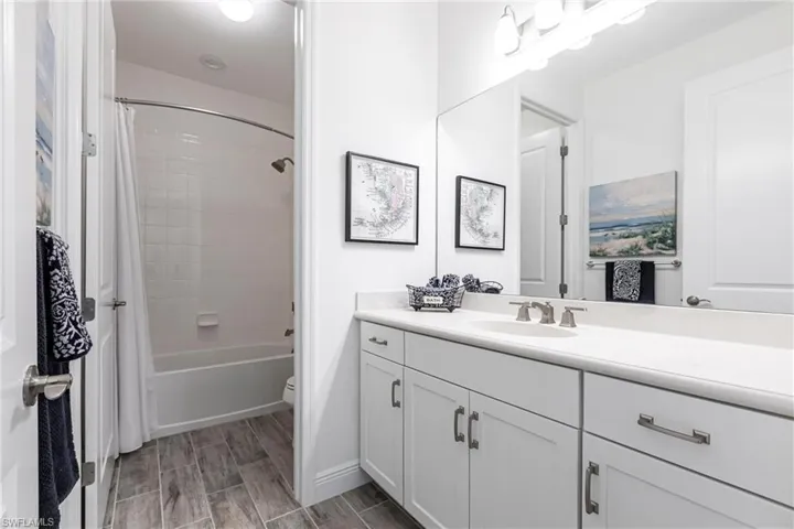 Full bathroom featuring shower / tub combo with curtain, and toilet with white cabinetry.