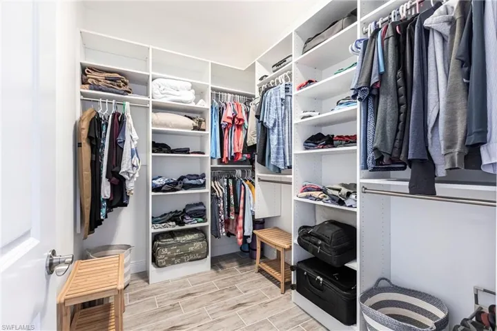 View of spacious closet all with custom cabinetry for added storage.
