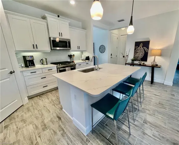 Kitchen with visible vents, an island with sink, quartz counter tops, stainless steel appliances, and tasteful backsplash
