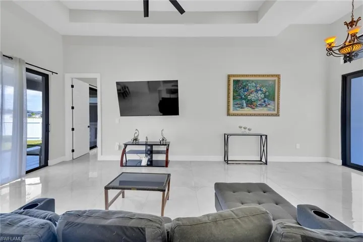 Living area featuring tile patterned floors, baseboards, and a ceiling fan