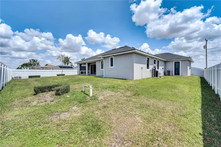 Back of house featuring a fenced backyard, cooling unit, a lawn, and stucco siding