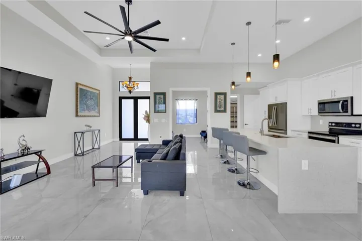 Living area featuring visible vents, baseboards, a raised ceiling, and recessed lighting