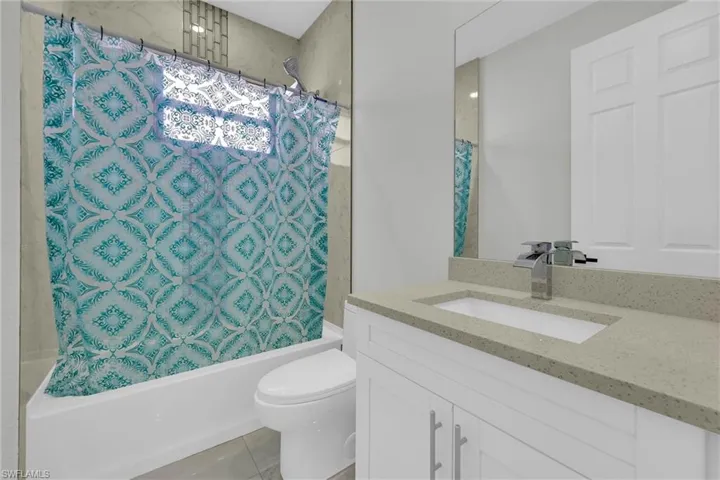 Bathroom featuring shower / tub combo, toilet, vanity, and tile patterned floors