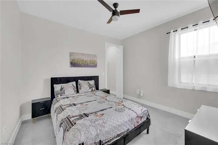 Bedroom with light tile patterned flooring, baseboards, and a ceiling fan