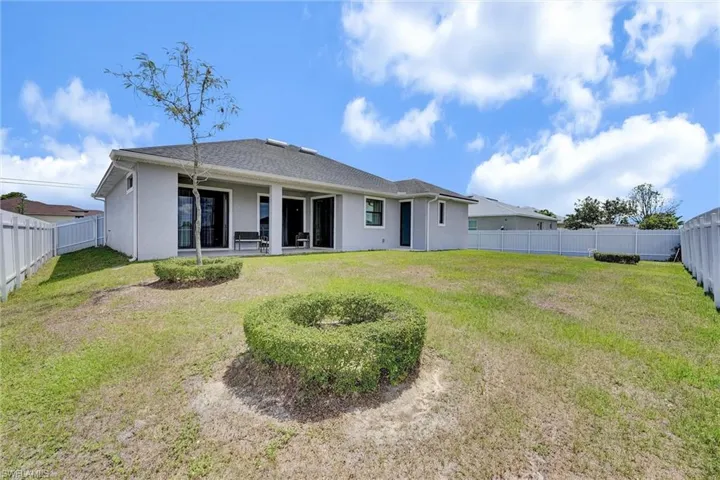 Rear view of property featuring a yard, stucco siding, and a fenced backyard