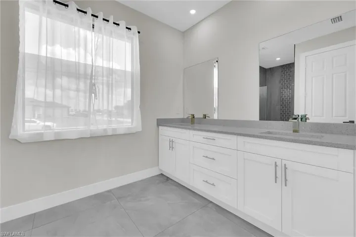 Bathroom with double vanity, a sink, baseboards, and recessed lighting