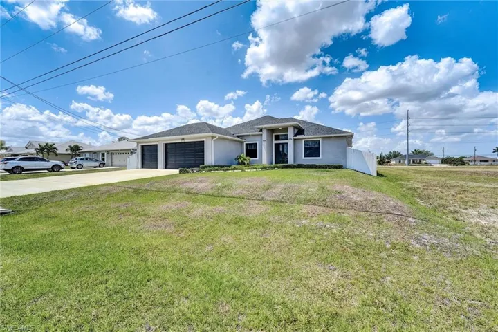 View of front of house with an attached garage, concrete driveway, stucco siding, and a front yard