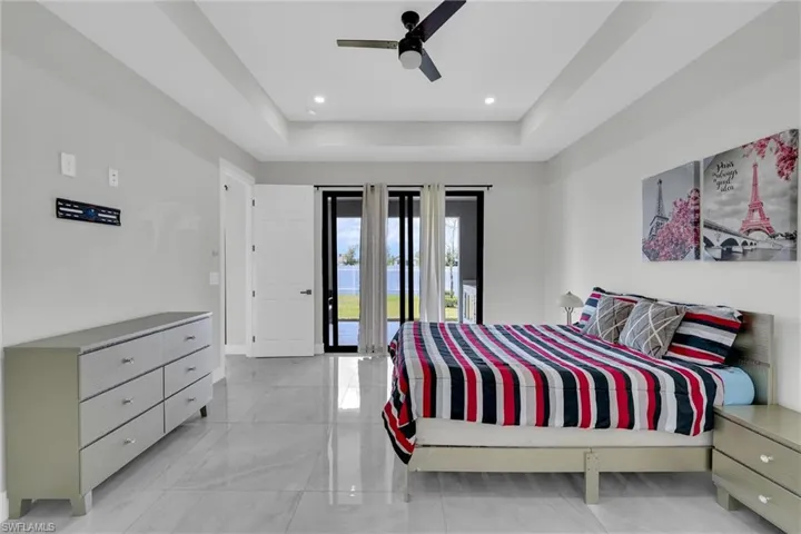 Bedroom with access to outside, baseboards, a tray ceiling, ceiling fan, and marble finish floor