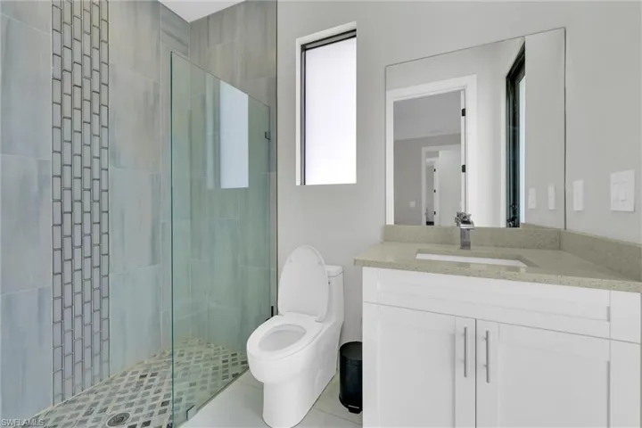Bathroom with toilet, a stall shower, and vanity