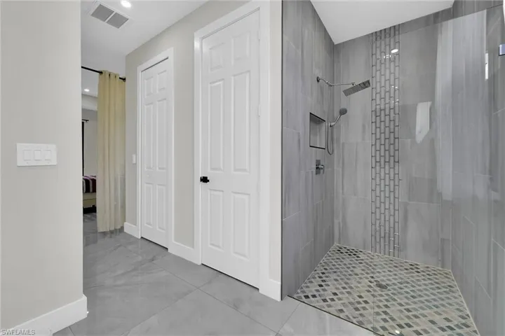 Ensuite bathroom featuring baseboards, recessed lighting, connected bathroom, tiled shower, and visible vents