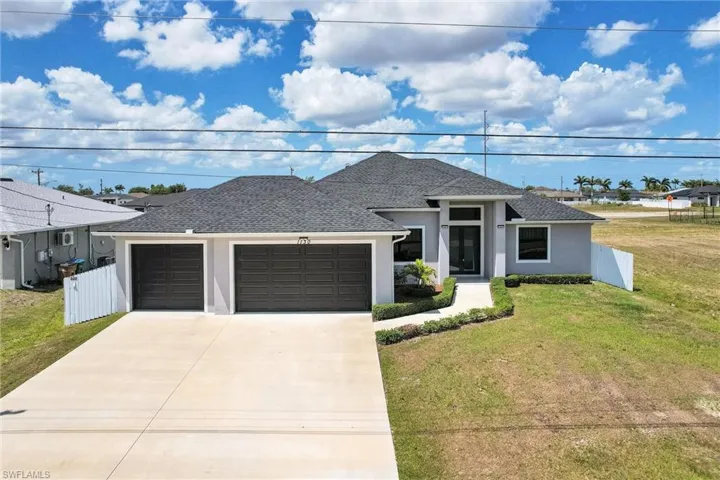 Prairie-style house featuring a front yard, fence, a shingled roof, and stucco siding