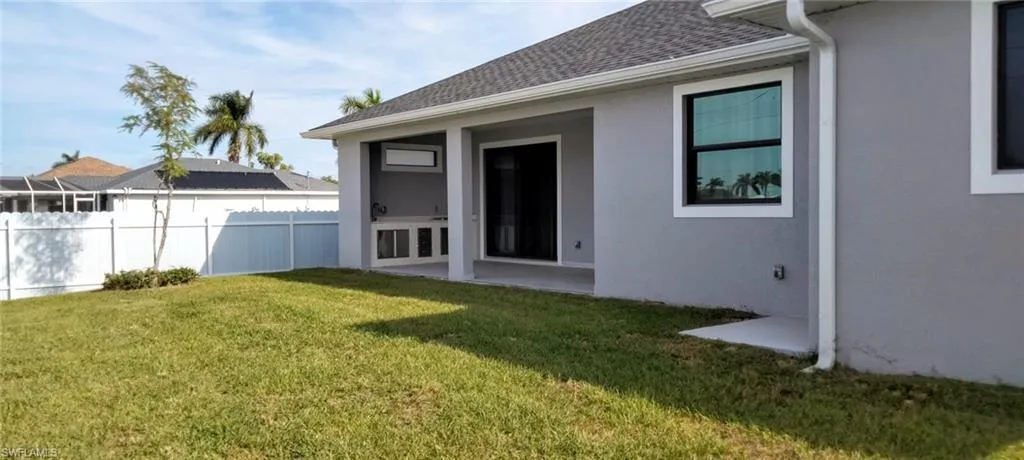 Rear view of property featuring a lawn and a patio