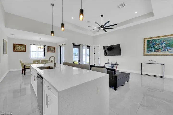 Kitchen with baseboards, open floor plan, visible vents, dishwasher, and a sink