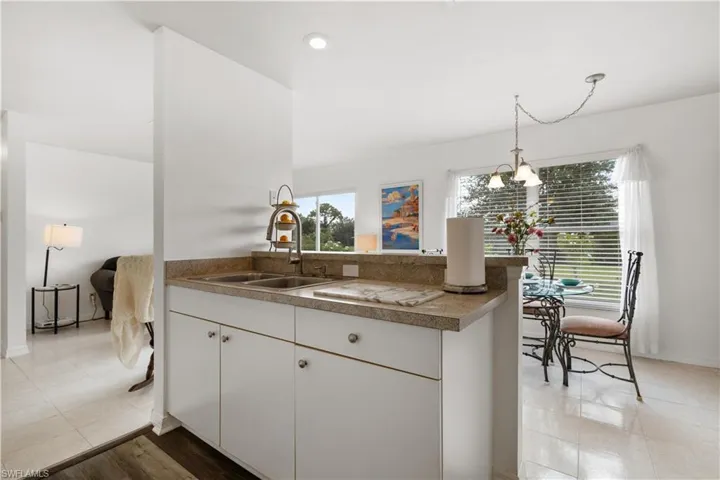 Kitchen featuring white cabinets, decorative light fixtures, sink, and kitchen peninsula