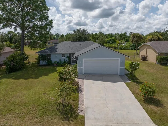 View of front facade featuring a front yard, a garage, and central AC unit
