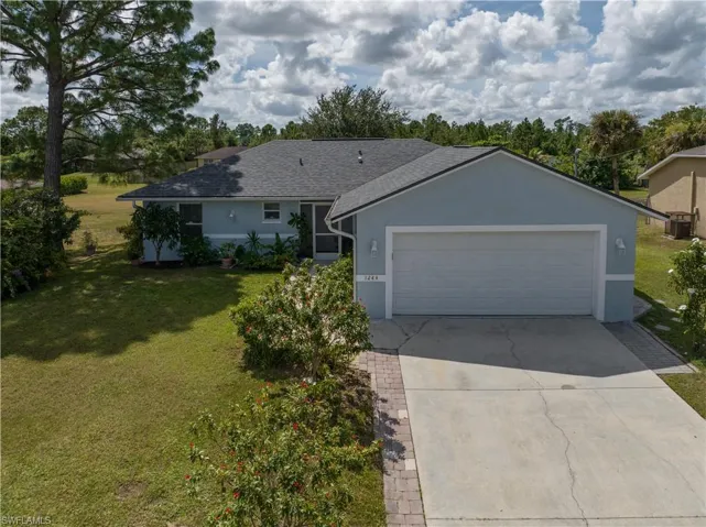 Ranch-style home featuring a front lawn, central air condition unit, and a garage