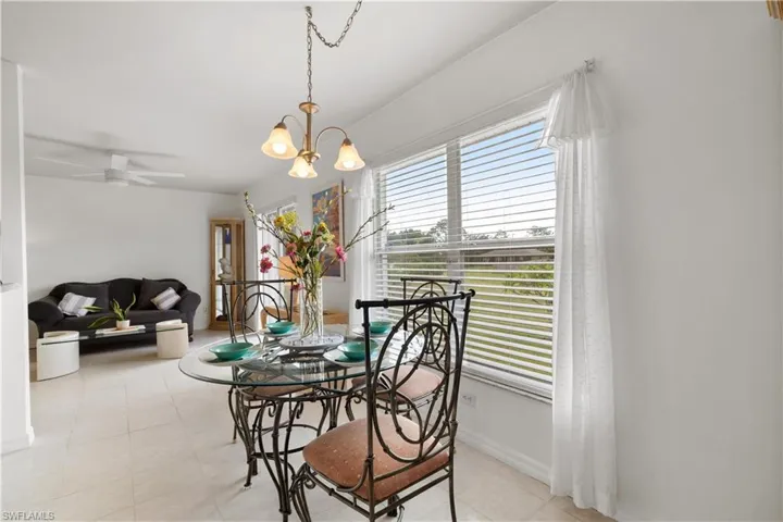 Tiled dining area with ceiling fan with notable chandelier