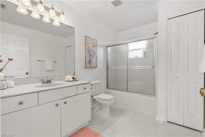 Full bathroom featuring shower / bath combination with glass door, vanity, and toilet