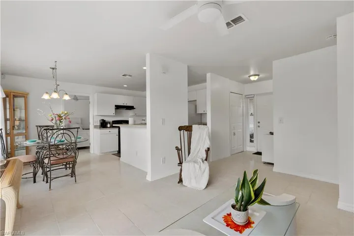 Living room featuring ceiling fan with notable chandelier and light tile patterned flooring