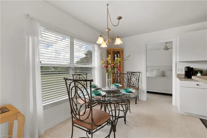 Tiled dining space featuring ceiling fan with notable chandelier