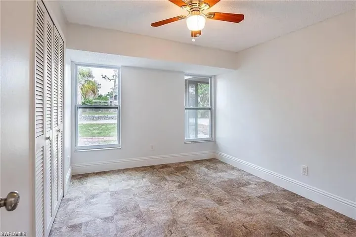 Unfurnished room with a textured ceiling, a ceiling fan, and stone finish flooring
