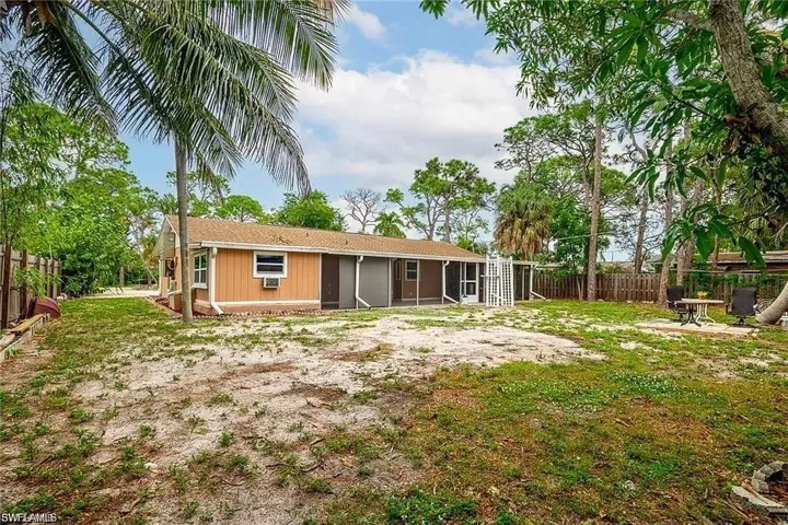 Rear view of house with a fenced backyard, a sunroom, and roof with shingles
