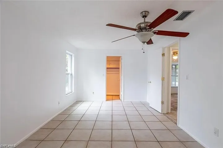 Unfurnished bedroom with light tile patterned flooring, a walk in closet, and ceiling fan