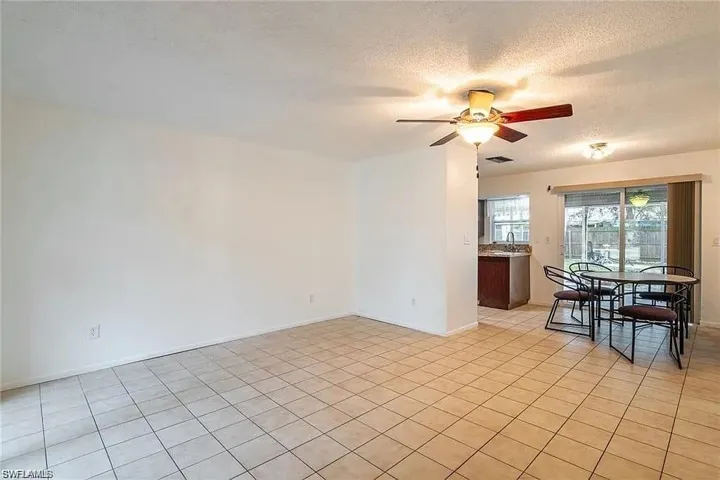 Empty room with a textured ceiling, ceiling fan, and light tile patterned floors