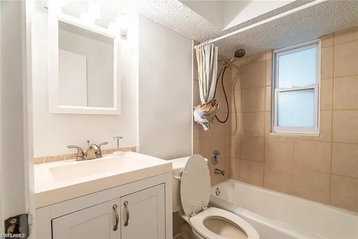 Full bathroom with shower / tub combo with curtain, a textured ceiling, and vanity